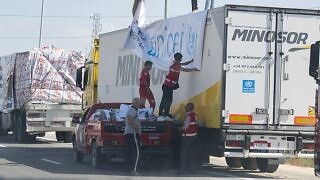 Aid workers load humanitarian supplies onto a truck near the Rafah border crossing between Egypt and Gaza